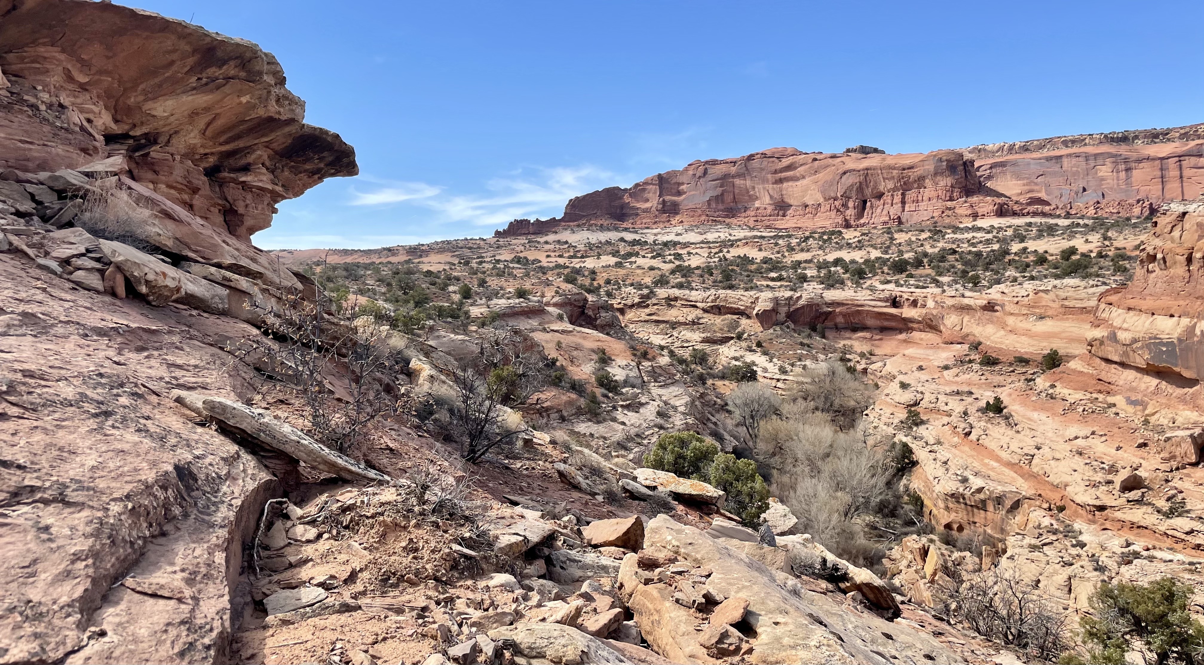 A landscape shot showing a deep valley bounded by rock overhangs and a tall mesa