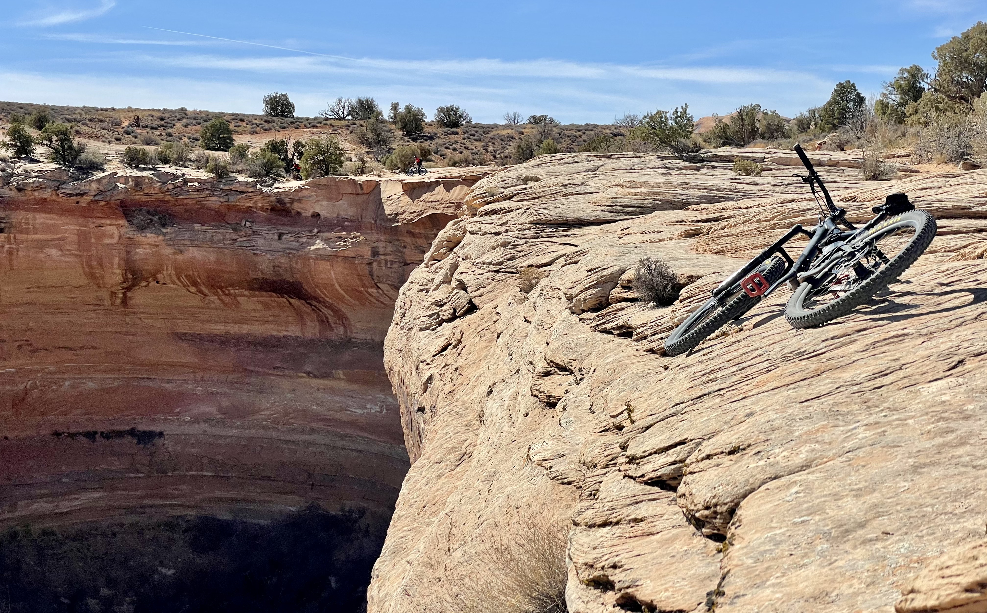 Photo of a mountain bike, laid precariously above a rounded cliff's edge