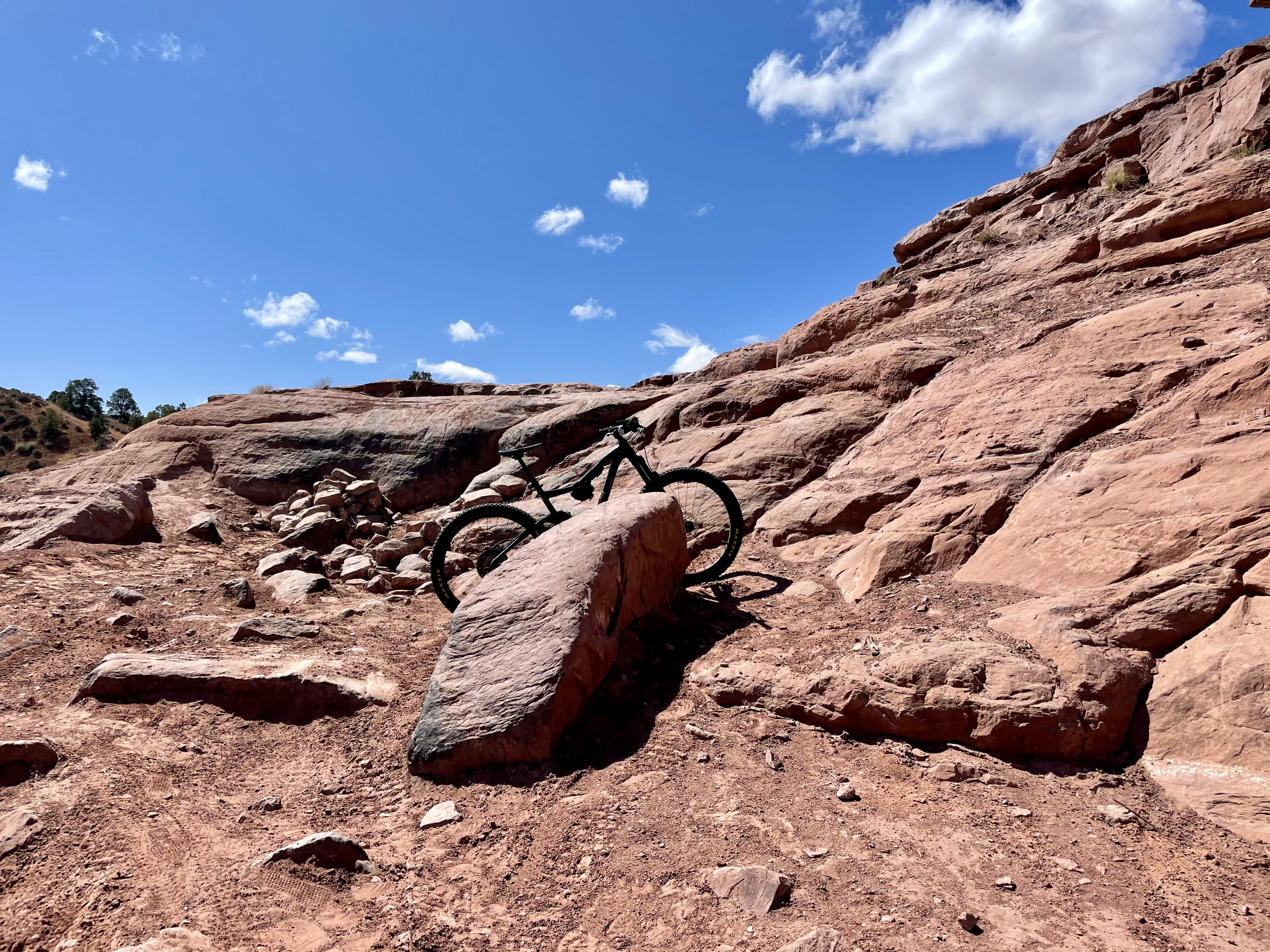 a bike sits behind a slightly taller rock, with a yet taller rock behind, where the path leads