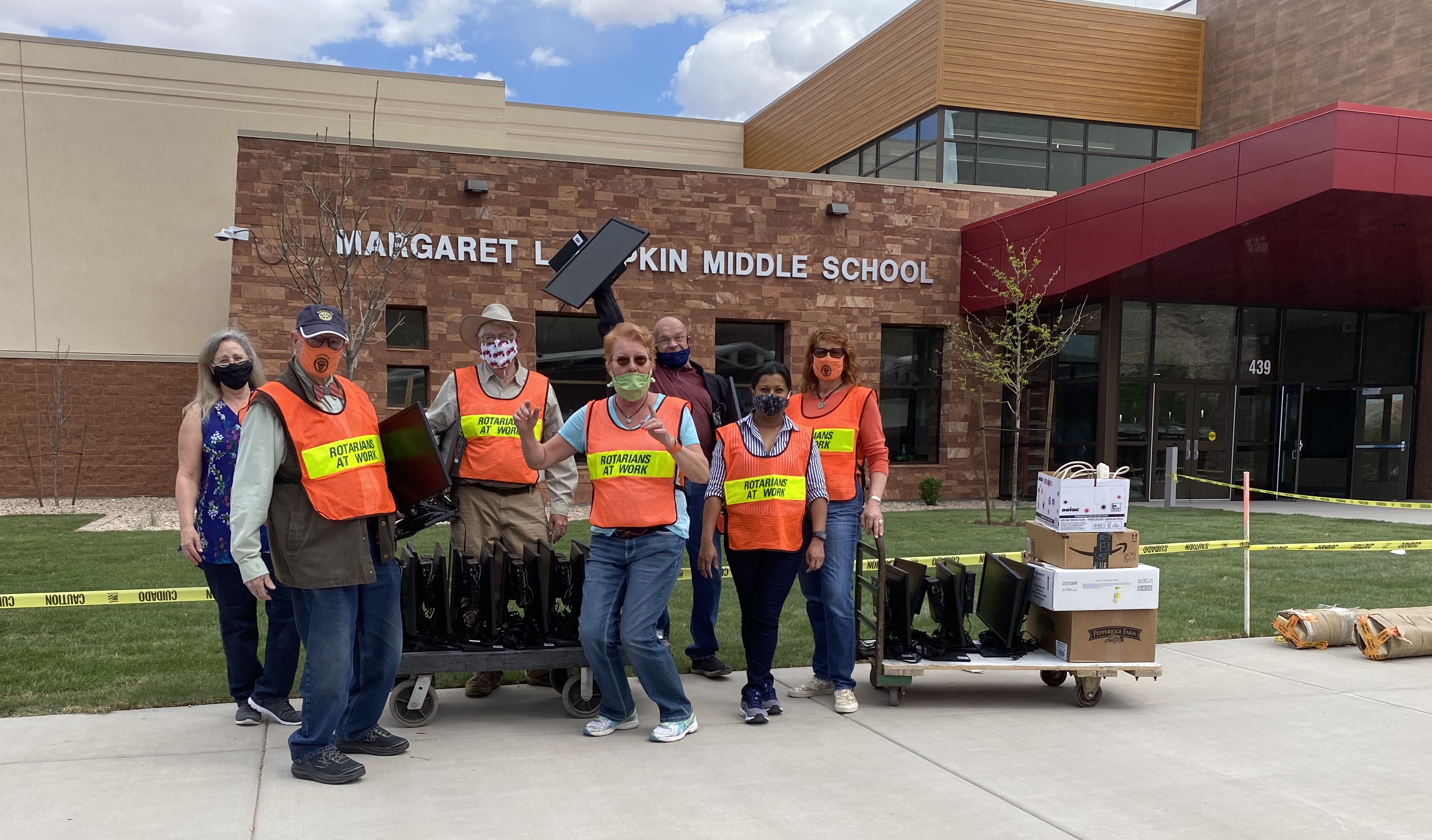 Members of the Moab Rotary Club wearing high-viz vests pose with computer equipment in front of the new middle school