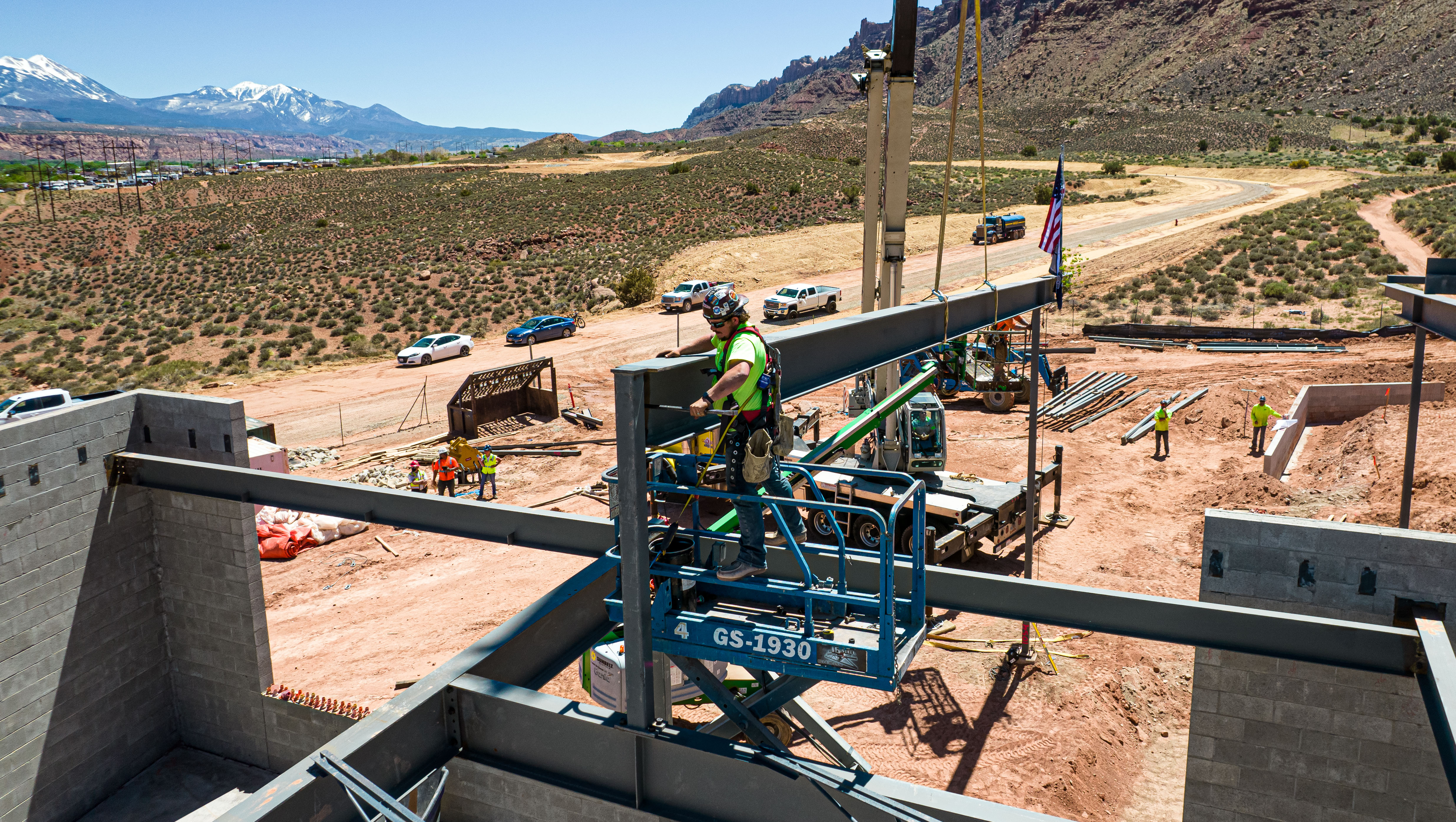 a construction worker secures the final support beam on the new Moab campus of Utah State University