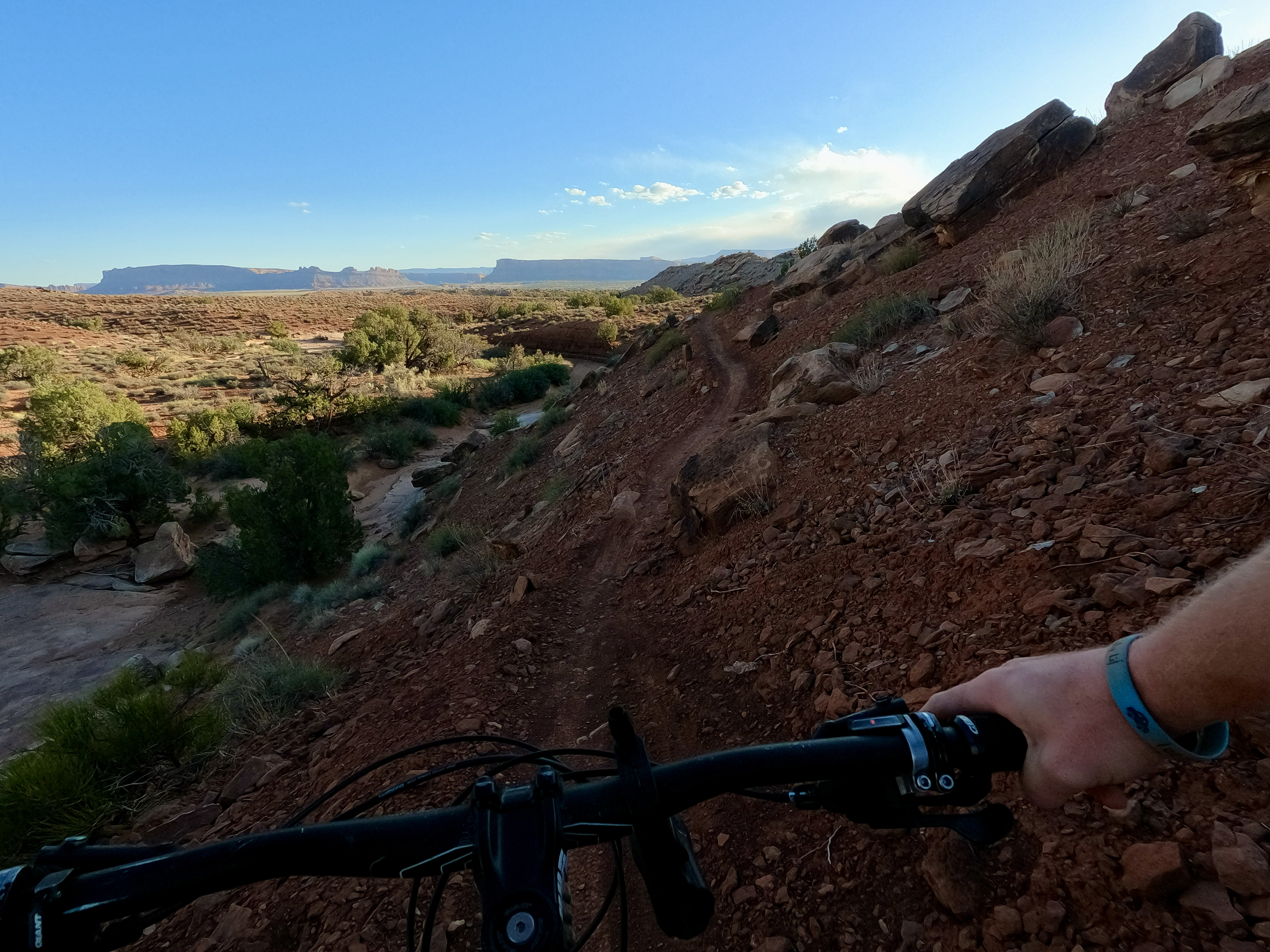 Photo from behind the handlebars of a shaded section of Gravitron, a trail in the Klonzo bike network in Moab, Utah