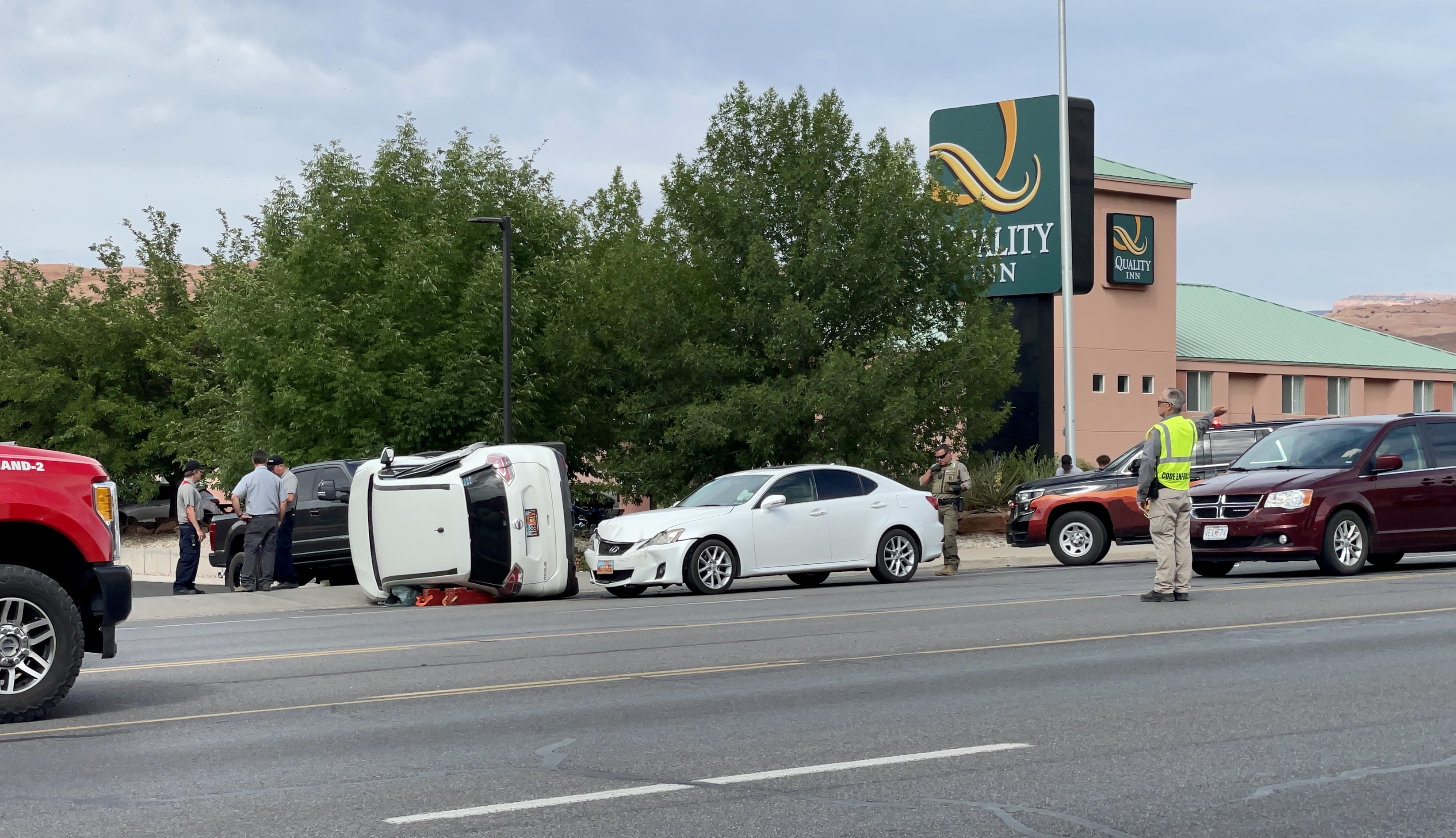 a car sits on its side in front of another vehicle with frontal damage