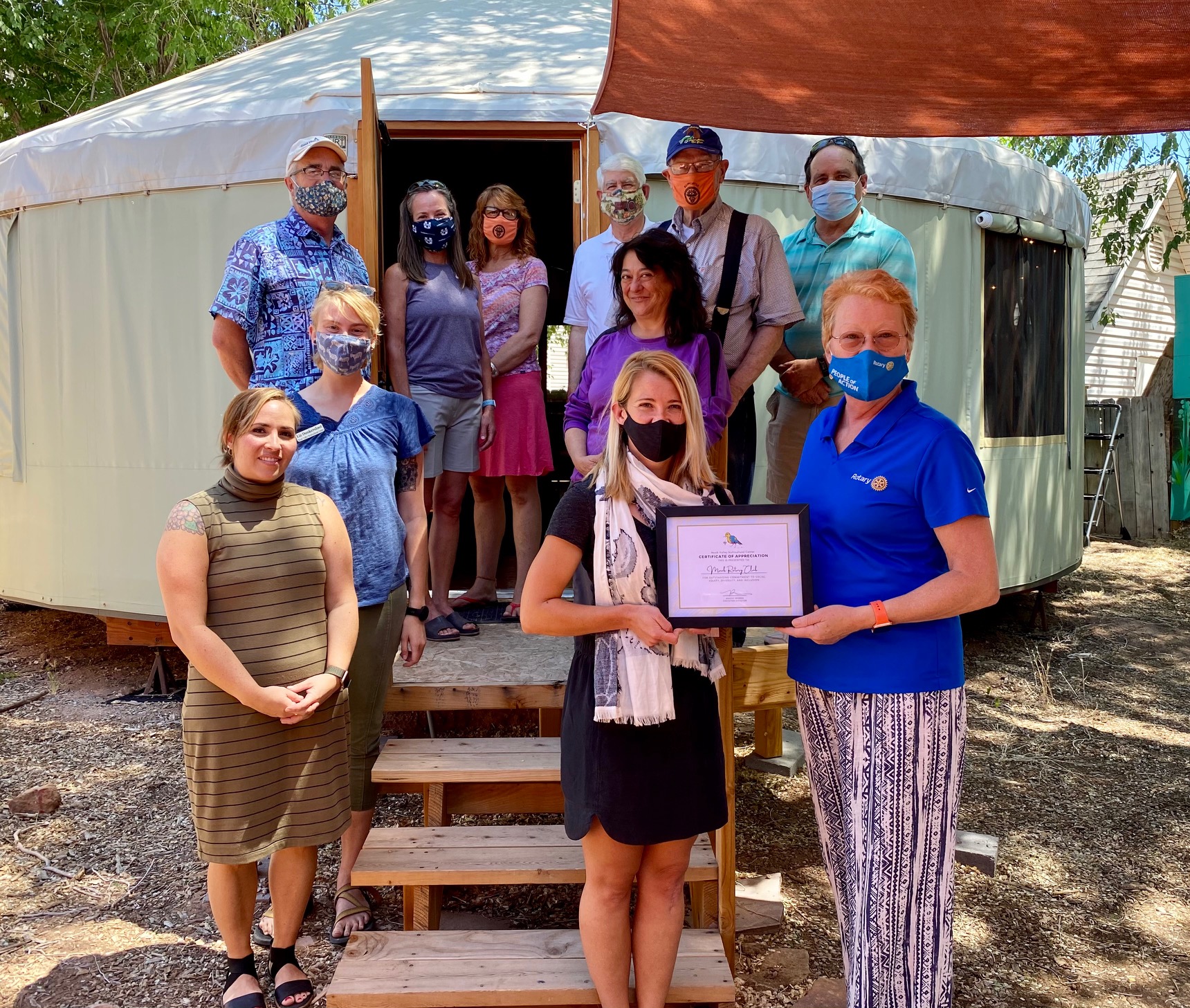 Staff of the Moab Valley Multicultural Center present a certificate of appreciation to the Moab Rotary Club in front of a yurt for the multicultural center that the club helped to fund. 