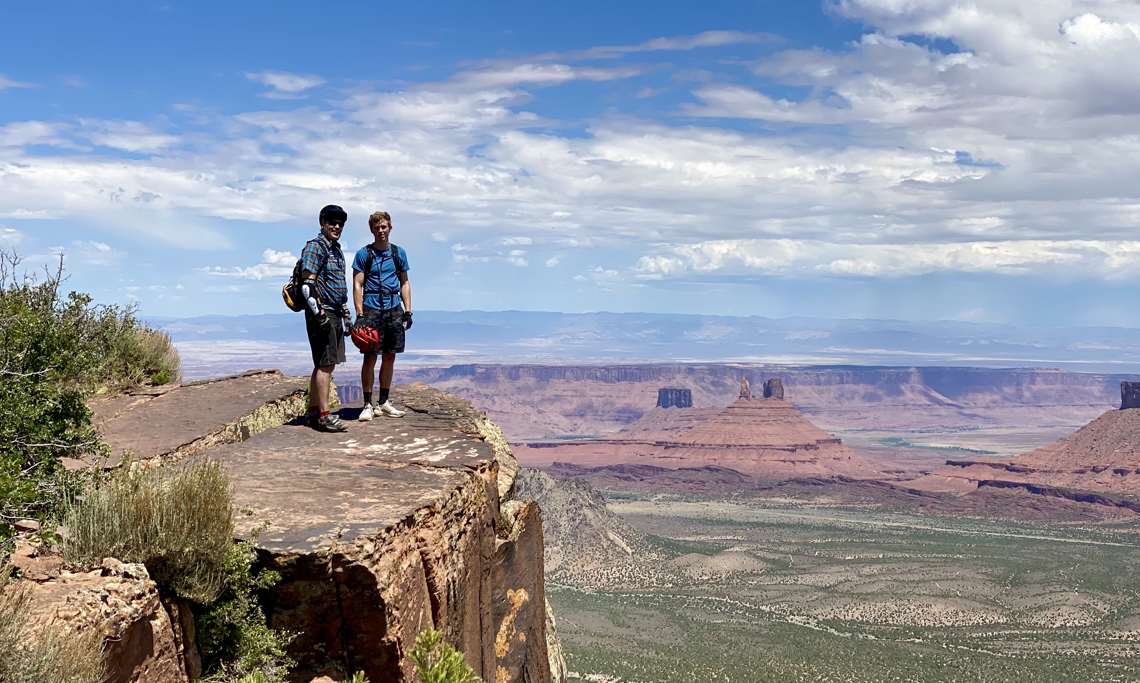 boy and his father stand near a cliff's edge overlooking Castleton Rock, Round Mountain, and the rest of Castle Valley